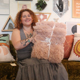 A woman holding the Pink Hero Dreamy Faux Fur Throw Blanket.