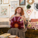 A woman holding the 'In Bloom' Wool Hook Pillow with Tassels.
