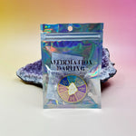The Word for Today Enamel Pin in its packaging against an amethyst piece all on a pink and yellow background.