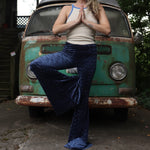 A woman wearing the Navy Velvet Bell Bottom Pants with a cream colored tank all in front of a vintage Volkswagen bus.