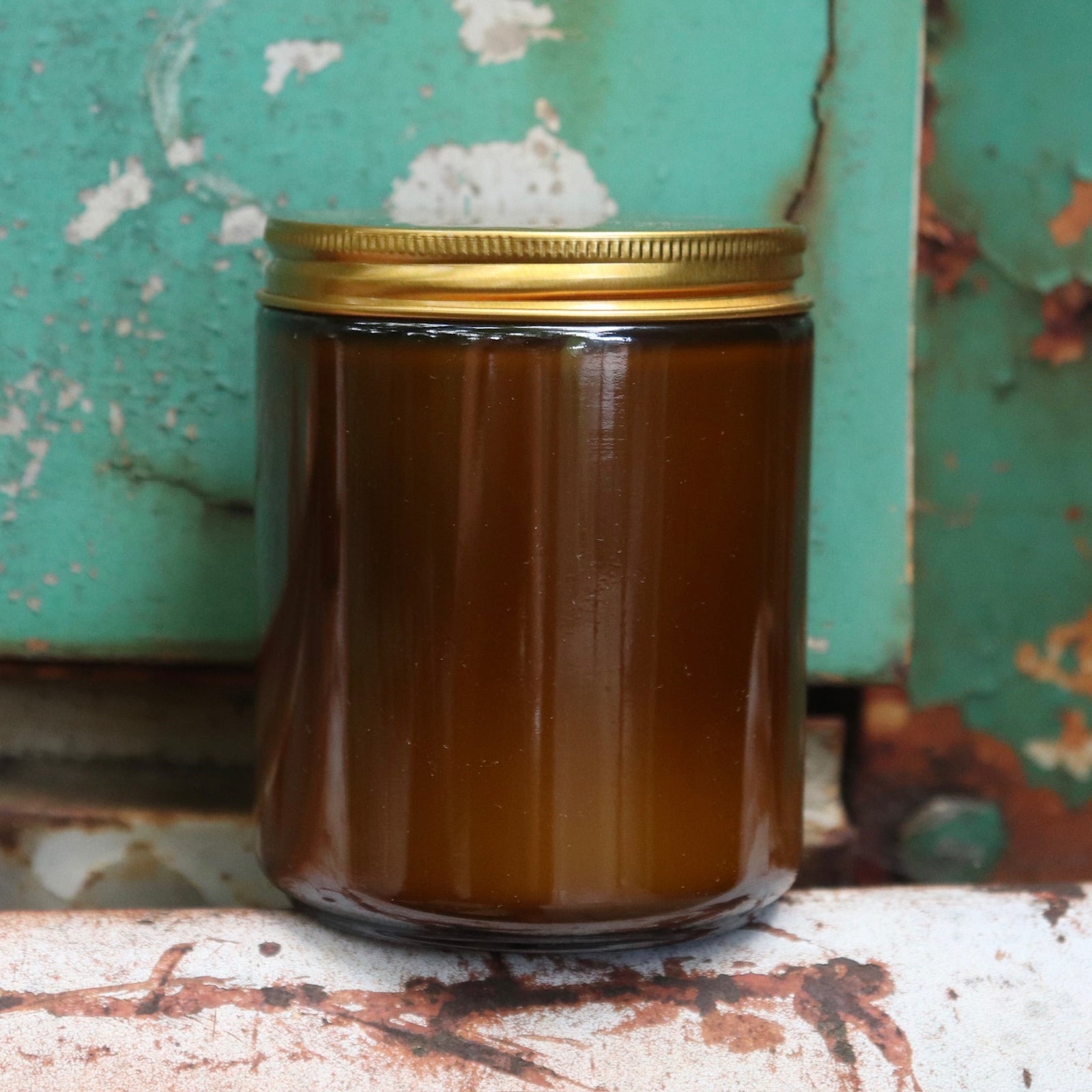 The back of a Shy Wolf candle on a white and teal rusty surface.