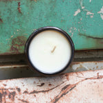 The inside of a Shy Wolf candle on a white and teal rusty surface.