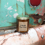 The I Walk the Line candle in front of a white and teal rusty background.