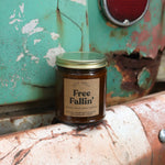 The Free Fallin' candle in front of a white and teal rusty background.