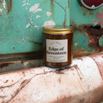 The Edge of Seventeen candle in front of a white and teal rusty background.