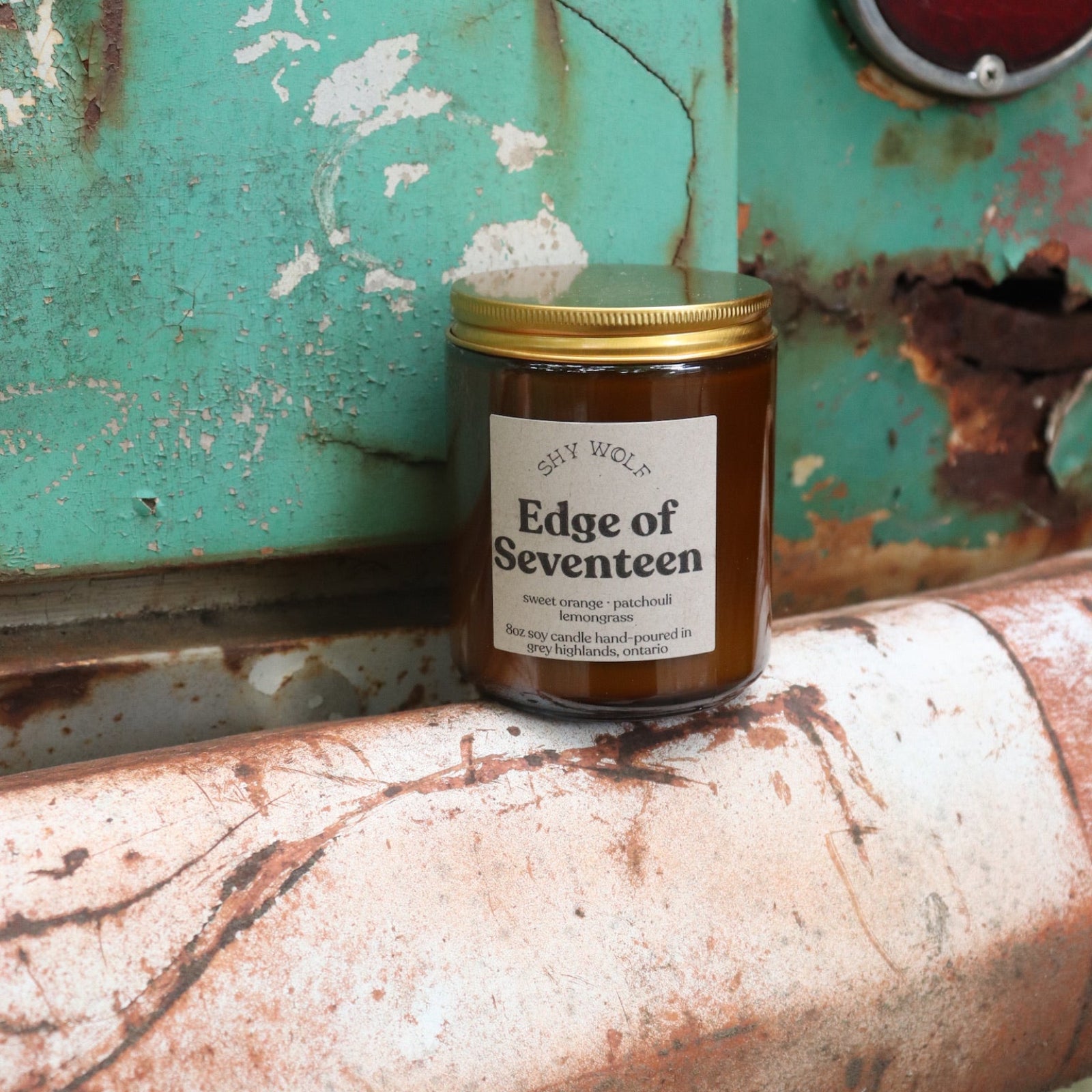 The Edge of Seventeen candle in front of a white and teal rusty background.