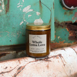 The Whole Lotta Love candle in front of a white and teal rusty background.