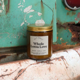 The Whole Lotta Love candle in front of a white and teal rusty background.