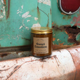 The Sweet Emotion candle in front of a white and teal rusty background.