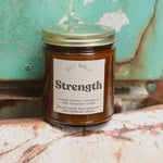 The Strength candle in front of a white and teal rusty background.