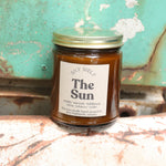 The Sun candle in front of a white and teal rusty background.