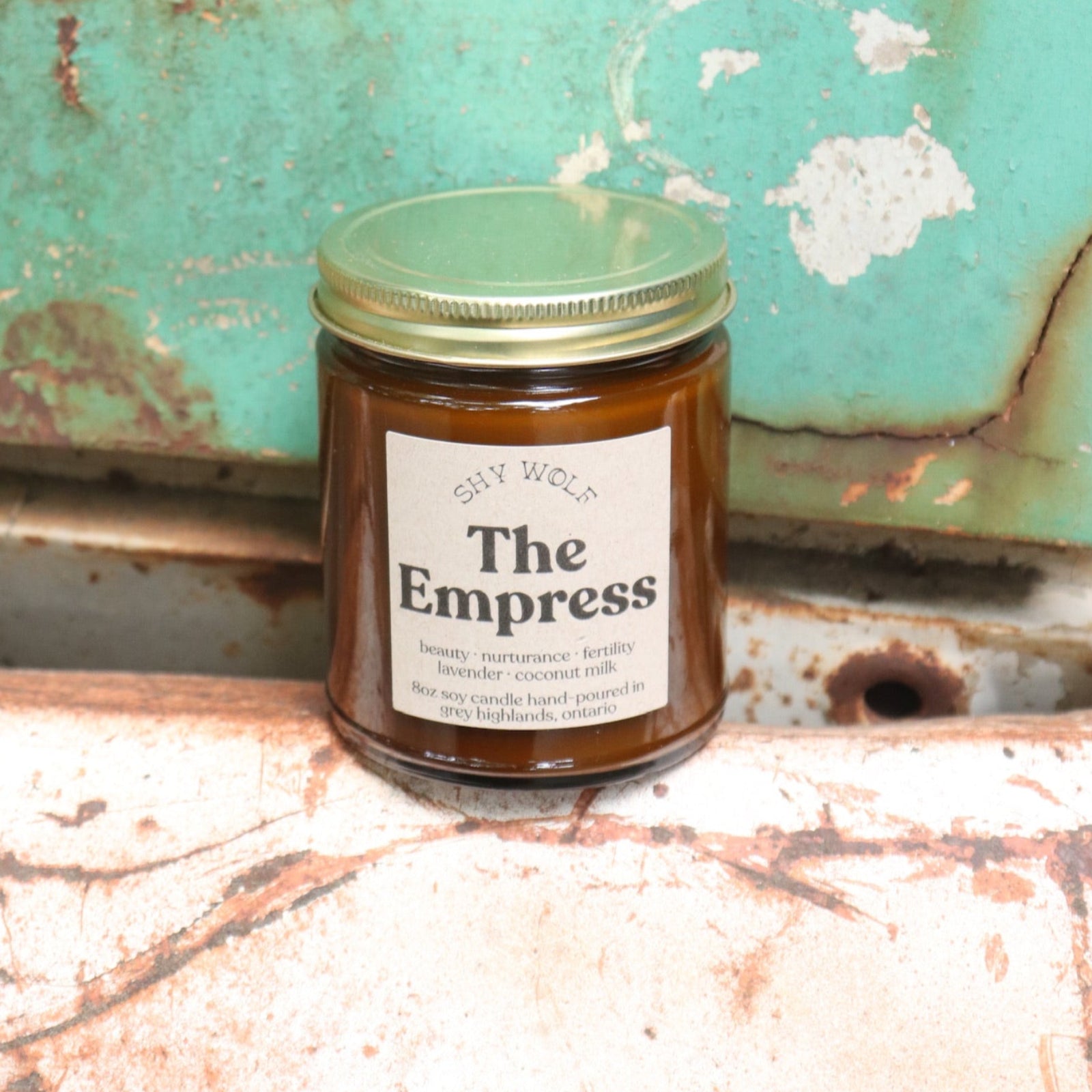 The Empress candle in front of a white and teal rusty background.