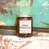 The High Priestess candle in front of a white and teal rusty background.