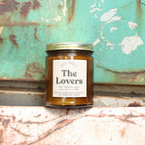 The Lovers candle in front of a white and teal rusty background.