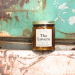 The Lovers candle in front of a white and teal rusty background.