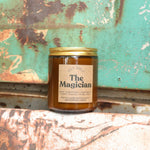 The Magician candle in front of a white and teal rusty background.