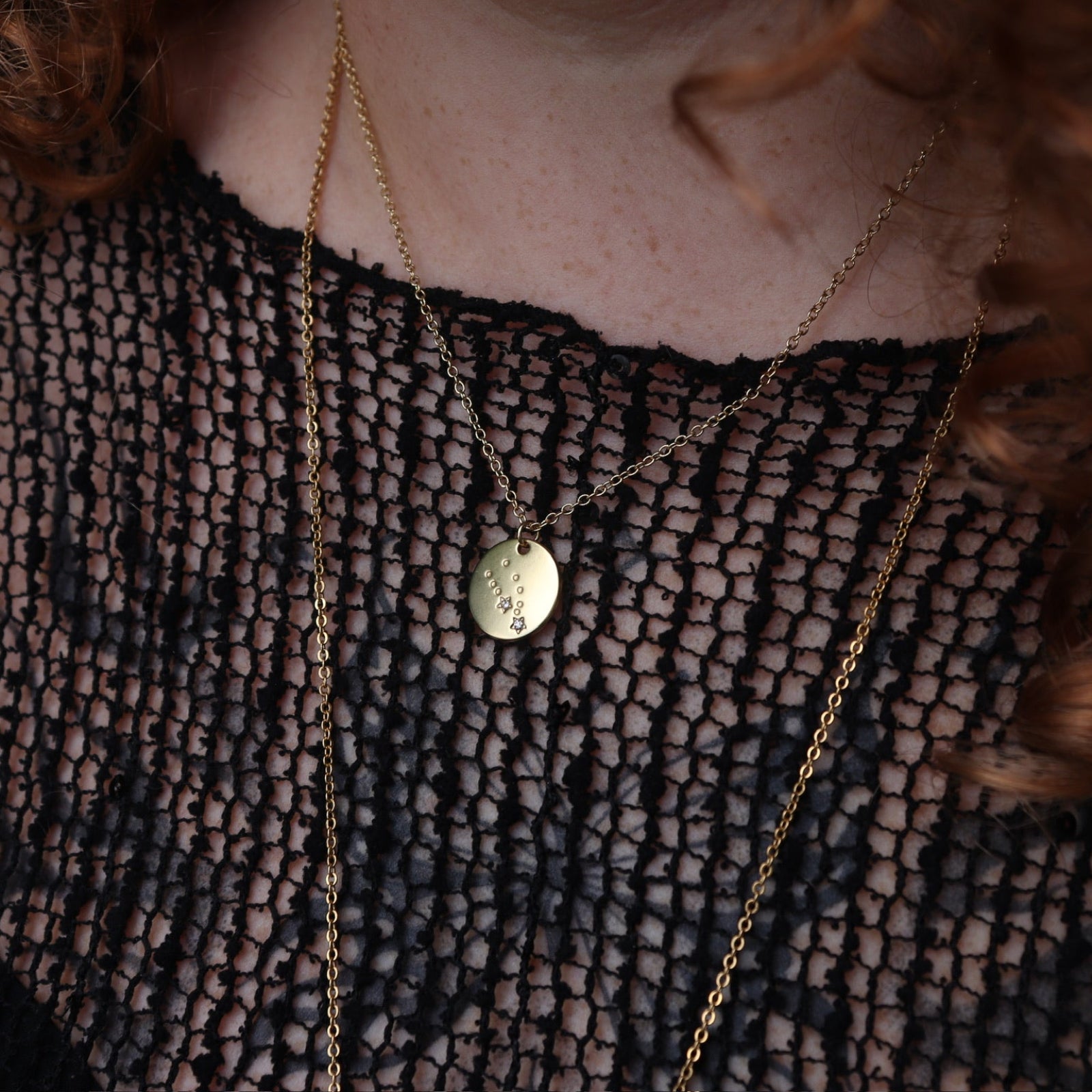 Someone wearing the Taurus 14k Gold Dipped Nickel-Free Zodiac Necklace with a black net top.
