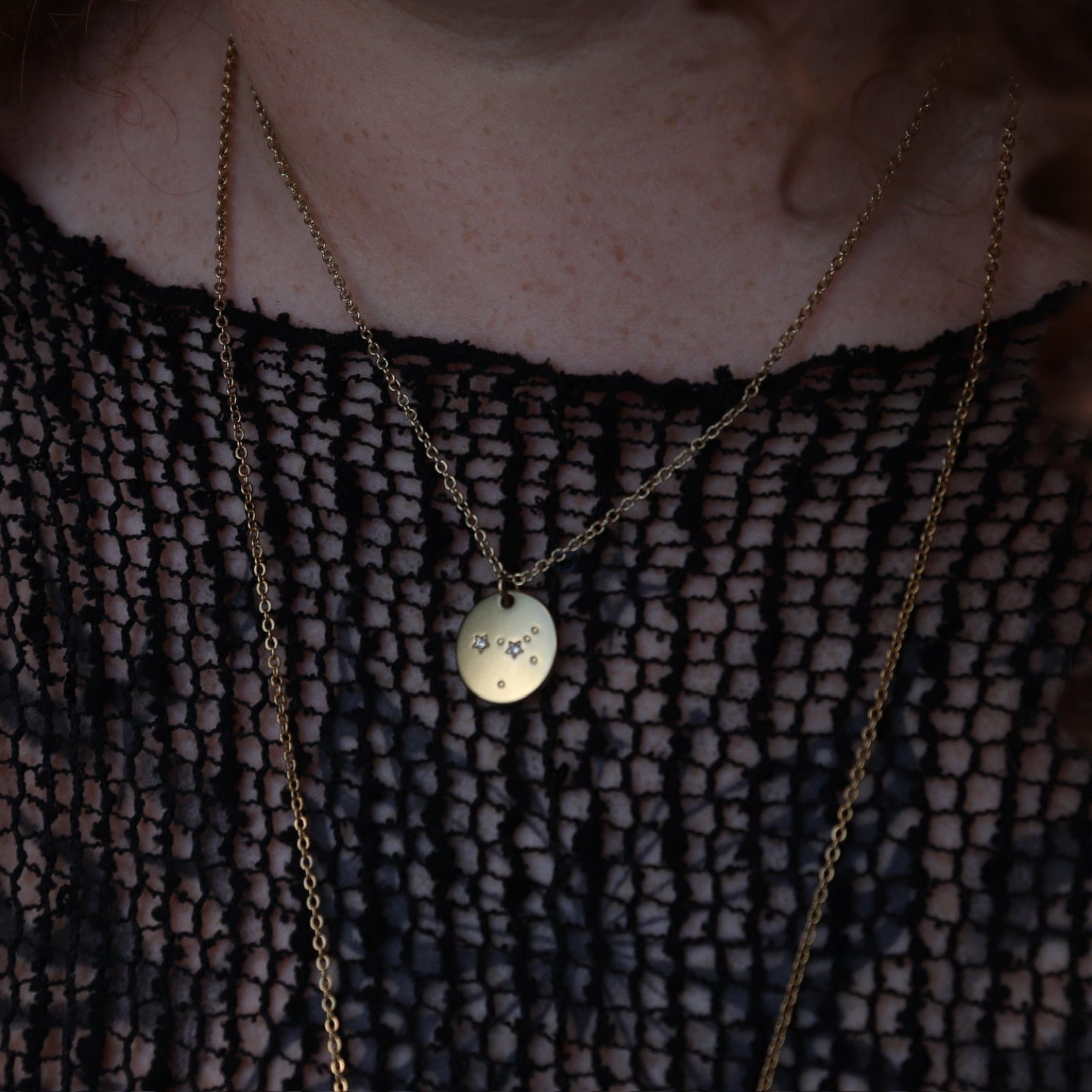 Someone wearing the Cancer 14k Gold Dipped Nickel-Free Zodiac Necklace with a black net top.