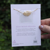 Someone holding the violet 14k Gold Dipped Nickel-Free Birth Month Flower Necklace in front of greenery showing off the back.