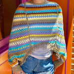 Someone wearing the coffee Vintage Rainbow Hollow Knit Sweater in front of an orange and pink wall with a window.