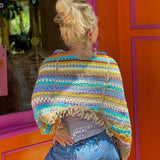Someone wearing the coffee Vintage Rainbow Hollow Knit Sweater in front of an orange and pink wall with a window.