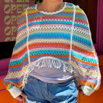 Someone wearing the white Vintage Rainbow Hollow Knit Sweater in front of an orange and pink wall with a window.