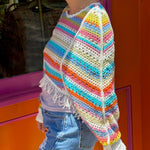 Someone wearing the white Vintage Rainbow Hollow Knit Sweater in front of an orange and pink wall with a window.