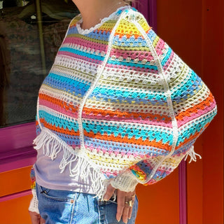 Someone wearing the white Vintage Rainbow Hollow Knit Sweater in front of an orange and pink wall with a window.