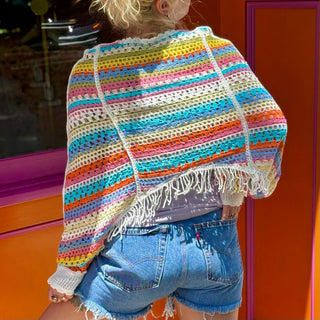 Someone wearing the white Vintage Rainbow Hollow Knit Sweater in front of an orange and pink wall with a window.