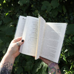 Someone holding one of the books open from the Witchcraft Boxed Set by Arin Murphy-Hiscock in front of greenery.