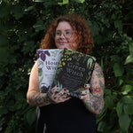 A woman holding the books from the Witchcraft Boxed Set by Arin Murphy-Hiscock in front of greenery.