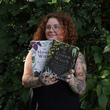 A woman holding the books from the Witchcraft Boxed Set by Arin Murphy-Hiscock in front of greenery.