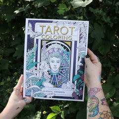 Someone holding the Tarot Coloring - Coloring Book in front of greenery.