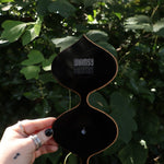 Someone holding the Retro Tear Drop Acrylic Mirror in front of greenery, showing off the back.