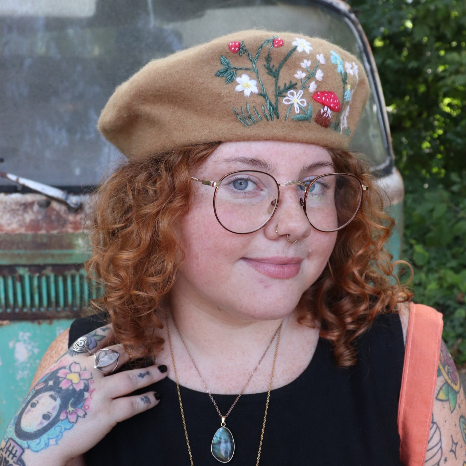 A woman wearing the beige Hand-Embroidered Floral Soft Beret Stylish Hat with a black shirt.