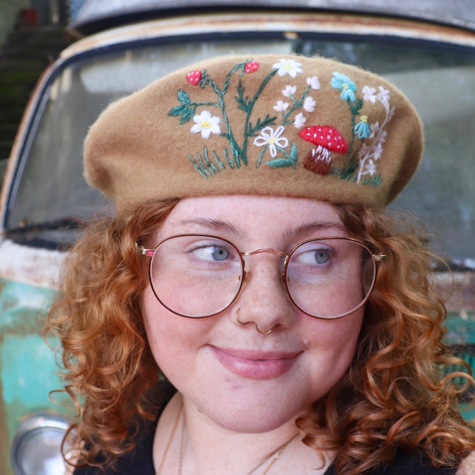 A woman wearing the beige Hand-Embroidered Floral Soft Beret Stylish Hat with a black shirt.