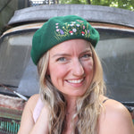 A woman wearing the green Hand-Embroidered Floral Soft Beret Stylish Hat with a navy floral dress.