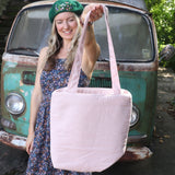 A woman holding the Daisy Embroidered Pastel Pink Linen Zipper Tote Bag showing off the back.