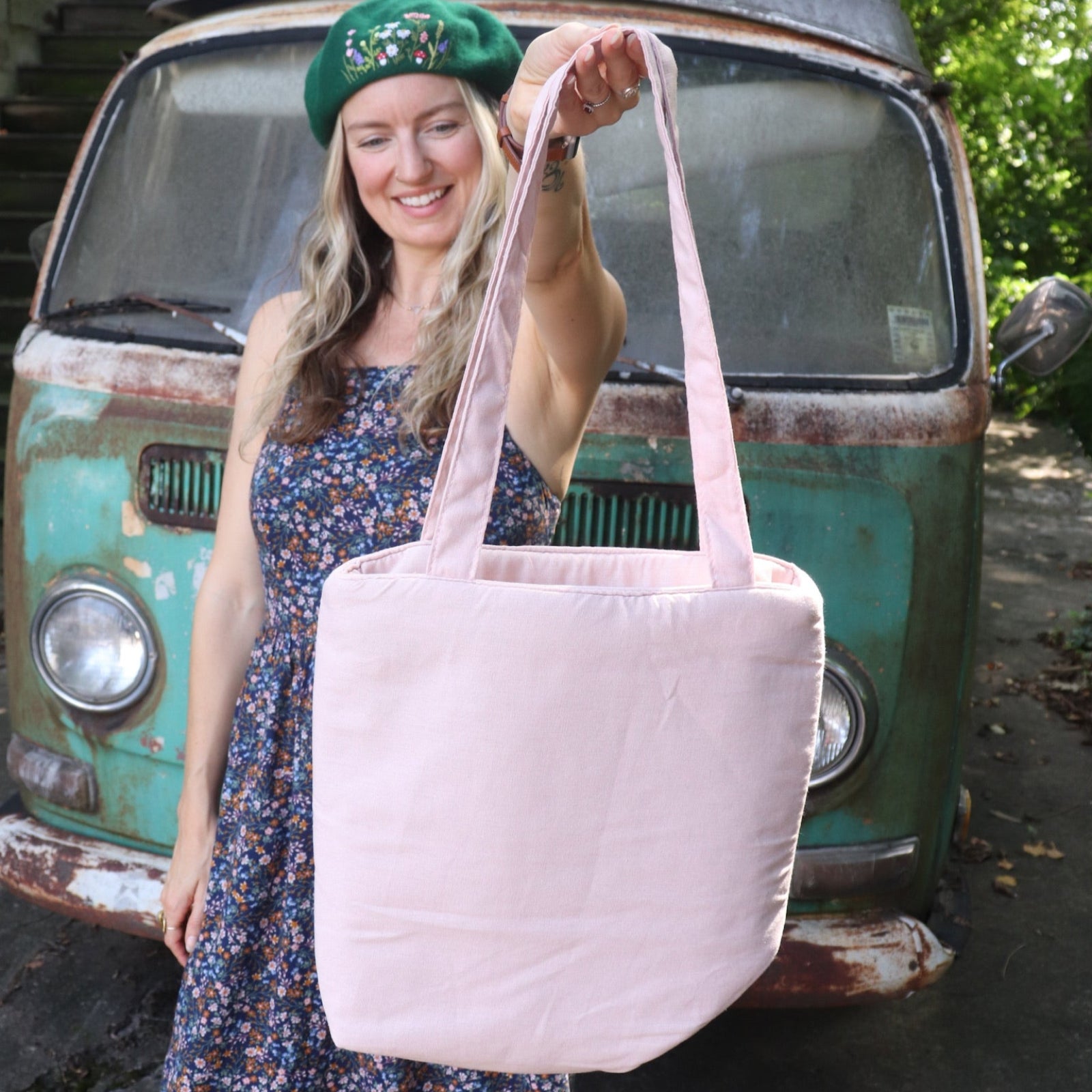 A woman holding the Daisy Embroidered Pastel Pink Linen Zipper Tote Bag showing off the back.