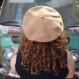 A woman wearing the beige Hand-Embroidered Floral Soft Beret Stylish Hat with a black shirt, showing off the back of the hat.