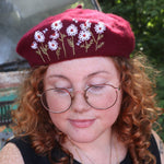 A woman wearing the red Hand-Embroidered Floral Soft Beret Stylish Hat with a black tank.