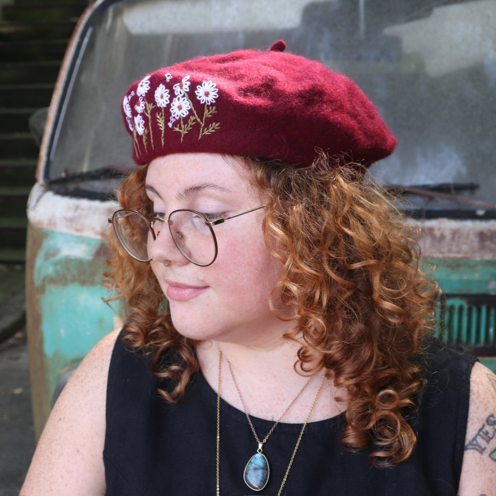 A woman wearing the red Hand-Embroidered Floral Soft Beret Stylish Hat with a black tank.