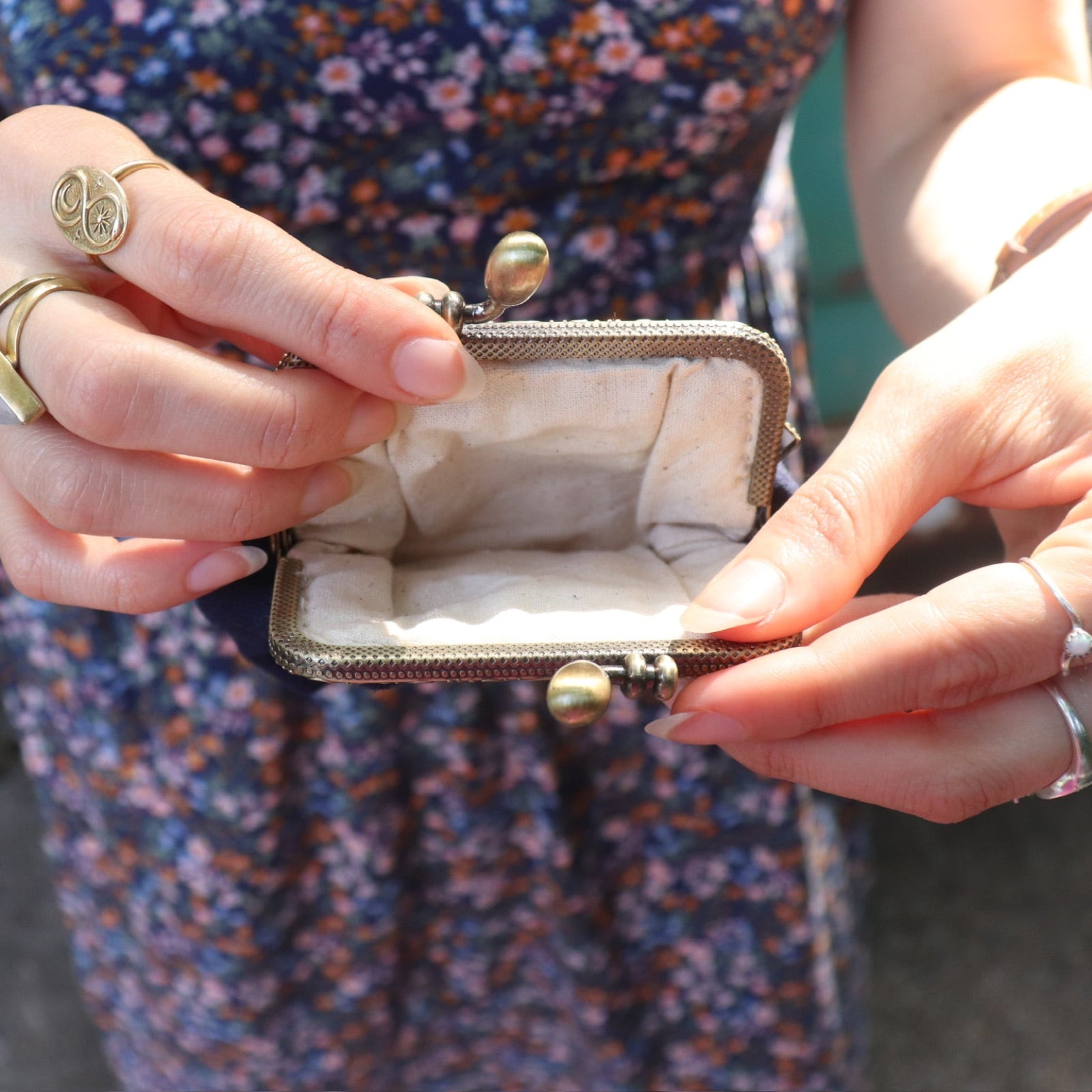 A woman in a navy floral dress holding the Deer Embroidered Navy Blue Coin Purse open showing the inside.