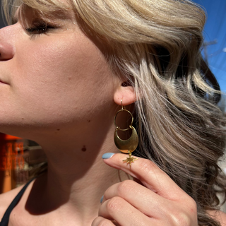 A woman wearing the Brass Star Dancer 2 inch. Earrings.