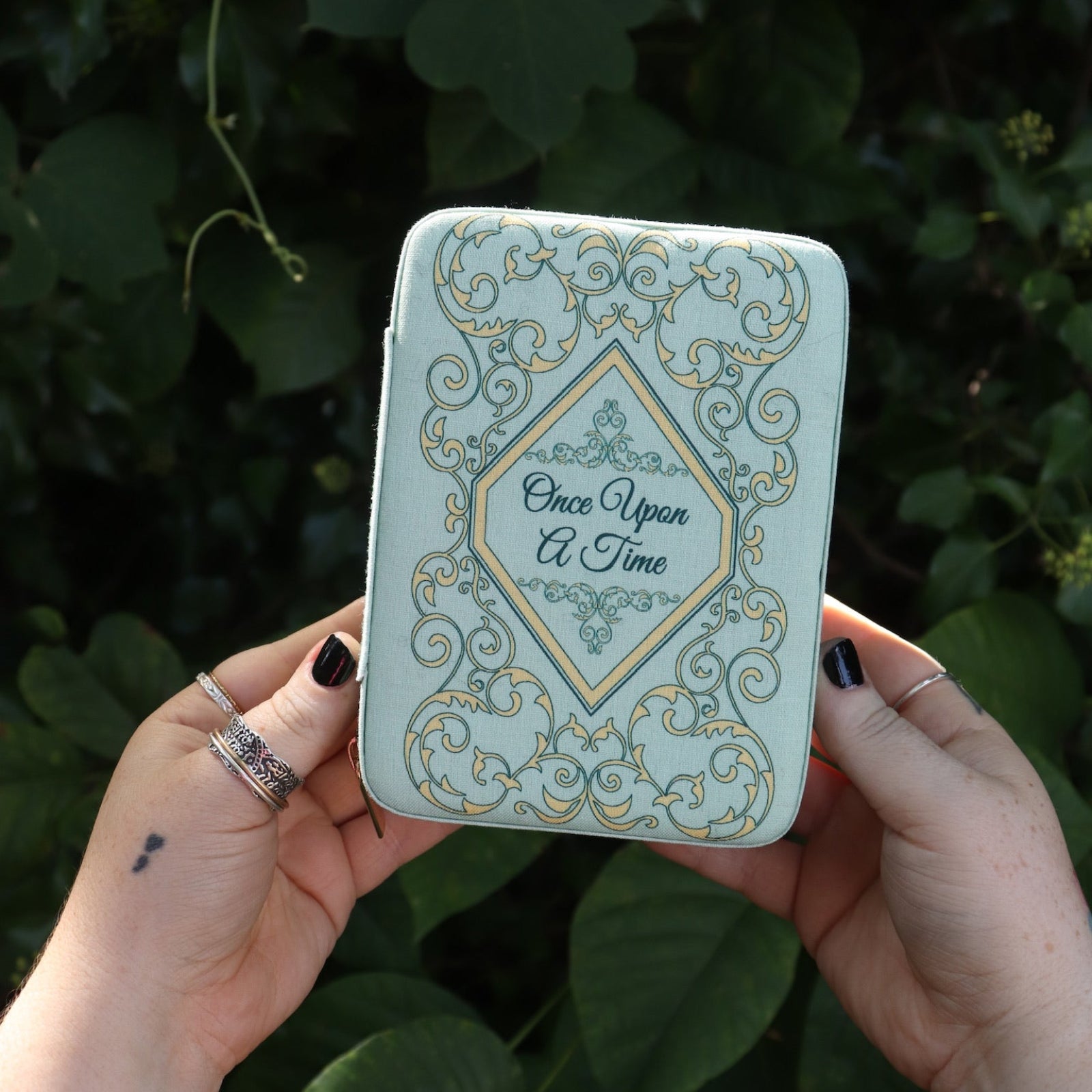 Someone holding the Once Upon a Time Travel Jewelry Organizer in front of greenery.