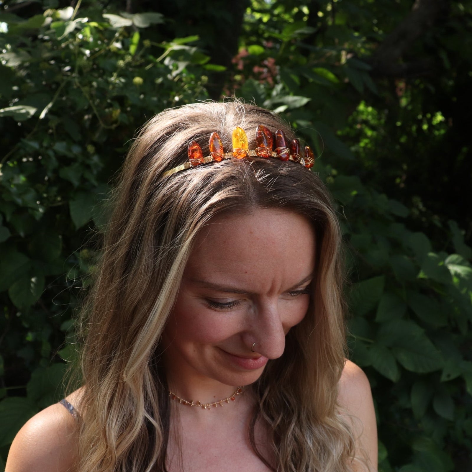 A woman wearing the Fairy Crown / Celtic Tiara - Amber: Gold in front of greenery.