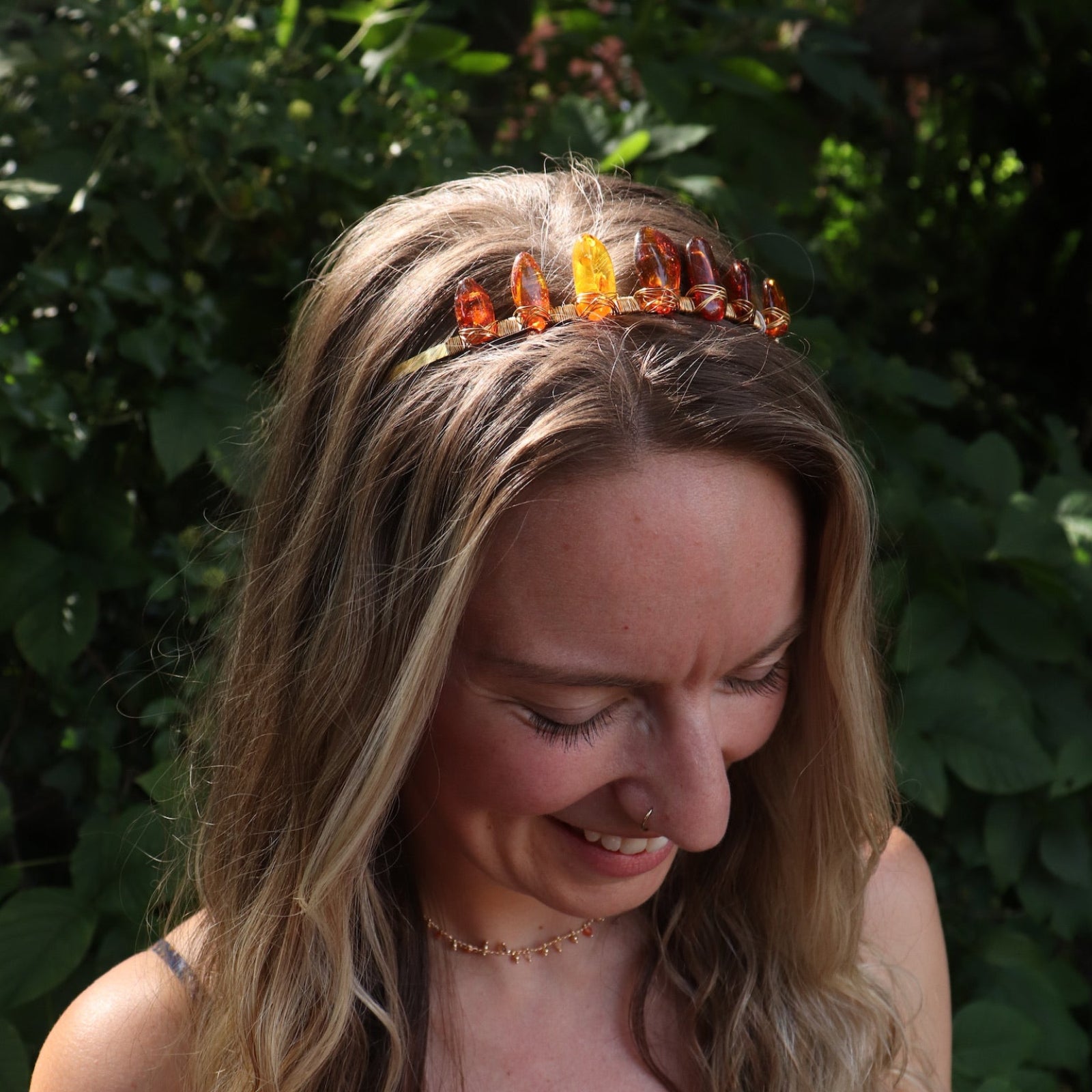 A woman wearing the Fairy Crown / Celtic Tiara - Amber: Gold in front of greenery.