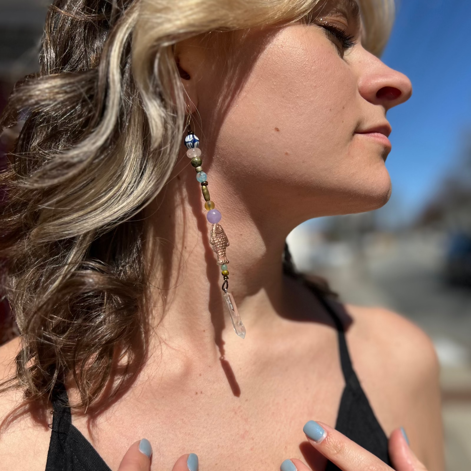 A woman wearing the Realm Earrings with a black dress.