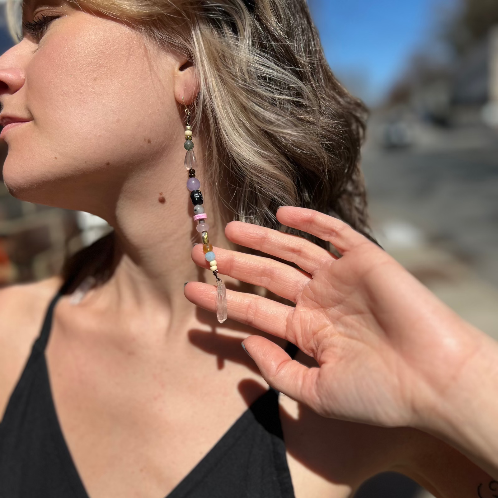 A woman wearing the Realm Earrings with a black dress.