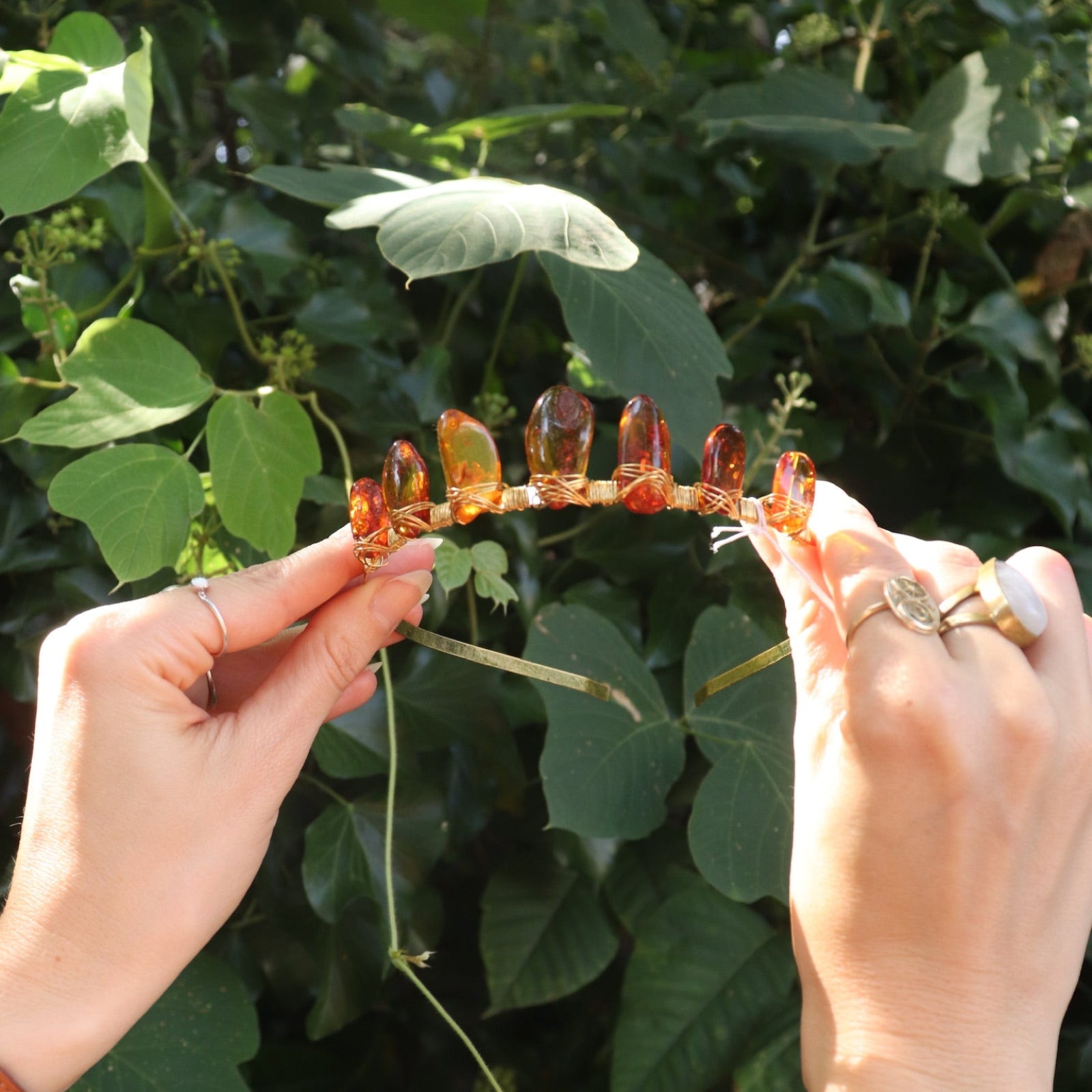 Someone holding the Fairy Crown / Celtic Tiara - Amber: Gold in front of greenery.